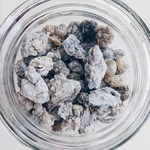 May include: A glass jar filled with grey and brown resin chunks. The resin is used for incense and aromatherapy.