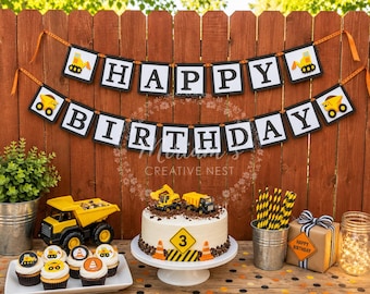 May include: A construction-themed birthday party set featuring a Happy Birthday banner with yellow dump truck icons, a white cake topped with toy trucks and a number 3 sign, cupcakes with construction toppers, and a gift box with a ribbon.