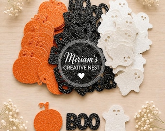 Puede incluir: Una colección de formas troqueladas con purpurina de temática de Halloween que incluye calabazas naranjas, texto negro "BOO" y fantasmas blancos. Un logotipo circular con el texto "Miriam's CREATIVE NEST" y un corazón está centrado.