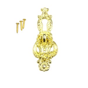 May include: Gold-toned metal decorative door or cabinet pull with ornate details and a keyhole. It comes with two small gold screws.