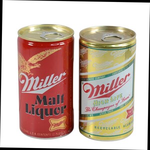 May include: Two vintage Miller beer cans. One is red with a gold eagle and the words "Miller Malt Liquor." The other is gold with "Miller High Life" and "The Champagne of Beers" printed on it. Both cans are aluminum.