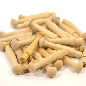 May include: A pile of wooden dowels with rounded ends. The dowels are light brown in color and are all the same size.