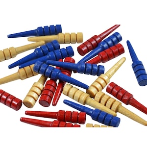 May include: A collection of wooden game pegs in blue, red, and natural wood colors. The pegs have a cylindrical top with grooves and a tapered, pointed end. These game pieces are likely for a board game.