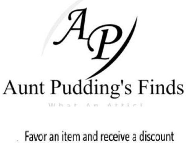May include: Black and white logo for "Aunt Pudding's Finds" with the letters "AP" in a stylized font. Below the logo is the text "Aunt Pudding's Finds" and the phrase "Favor an item and receive a discount".