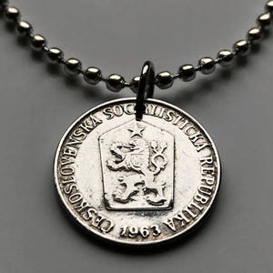 Puede incluir: Collar de plata con un colgante redondo que presenta el escudo de armas de Checoslovaquia. El colgante tiene el texto "Ceskoslovenska Socialisticka Republika 1963" alrededor del borde.