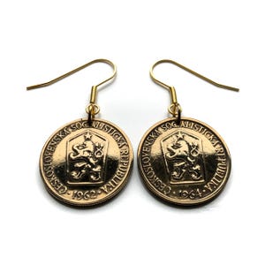 Puede incluir: Pendientes de color dorado con monedas checoslovacas con el texto "Ceskoslovenska Socialisticka Republika" y los años "1962" y "1964".