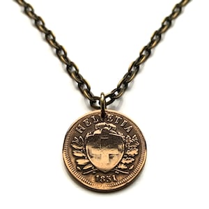May include: A gold chain necklace with a copper coin pendant featuring the Swiss coat of arms and the inscription "Helvetia 1851".