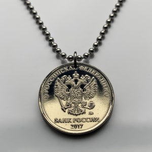 May include: A silver necklace with a round pendant featuring the Russian coat of arms and the text "Российская Федерация" and "БАНК РОССИИ 2017".