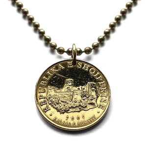 Puede incluir: Un collar de oro con un colgante de moneda de oro con el texto "Republika e Shqiperise" y "2000 Kalaja e Beratit".