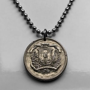 Könnte beinhalten: Eine silberfarbene Halskette mit einem runden Münzanhänger. Die Münze hat ein geprägtes Design mit Wappen und Text. Die Halskette besteht aus kleinen, runden Kugeln. Der Münzdurchmesser beträgt ca. 3 cm.