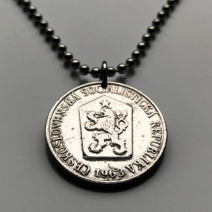 Puede incluir: Un collar de plata con un colgante de moneda que presenta el texto "Ceskoslovenska Socialisticka Republika 1963" y un emblema de león.