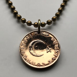May include: A gold necklace with a Turkish Lira coin pendant featuring a crescent moon and star. The coin has the text "CUMHURIYETI TURKIYE" around the edge.
