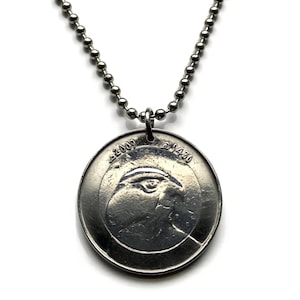 May include: A silver-colored pendant necklace featuring a circular coin-like charm. The charm has a profile image and the numbers "2009" and "1430" etched on it. The necklace chain is made of small, round beads.