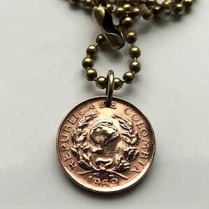 May include: A gold chain necklace with a brass clasp and a copper-colored Colombian coin pendant. The coin features the text "REPUBLICA DE COLOMBIA" and the year "1969".