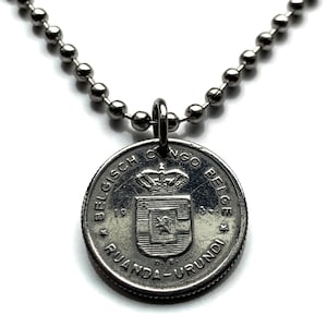 May include: A silver-colored coin pendant necklace. The pendant is a coin with text around the edge and a crest in the center. The necklace chain is made of small, round, silver-colored beads.