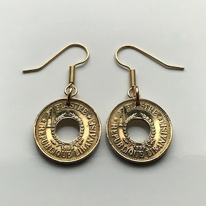May include: Gold earrings made from 1955 Lebanese 1 Piastre coins. The coins have been cut in half and the center removed to create a circular opening. The earrings are hanging from gold hooks.