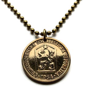 Puede incluir: Collar de oro con un colgante de moneda de la República Checa con un león y el texto "Ceskoslovenska Socialisticka Republika 1964".