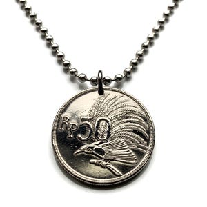 Puede incluir: Un collar de plata con un colgante de moneda de plata que presenta un pájaro con una cresta de plumas y el texto "Rp 50".