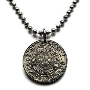 Può includere: Collana con pendente color argento con una moneta rotonda con un emblema e testo. La moneta è attaccata a una collana a catena a sfera. La moneta ha il testo "MARKAZIY BANKI" e "2018".