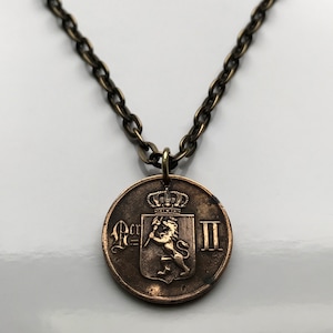 Puede incluir: Un collar de oro con un colgante de bronce que representa un león sosteniendo una lanza y una corona encima. El colgante también tiene el texto "R=III".