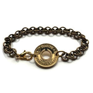May include: A gold-toned bracelet with a 1 Piastre coin charm from the Republic of Lebanon. The coin features the year 1955 and the text "1 Piastre Republique Libanaise".