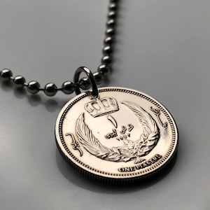 Puede incluir: Un collar de plata con un colgante de moneda de plata que presenta una corona, texto árabe y las palabras "One Piastre".