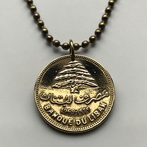 May include: Gold necklace with a round pendant featuring a cedar tree and the text "Banque du Liban 1969-1974" in Arabic and French.