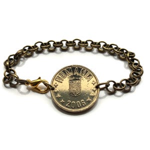 May include: A gold chain bracelet with a Romanian coin charm featuring the coat of arms and the year 2006.