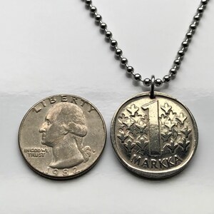May include: A silver necklace with a silver coin pendant. The coin has the number "1" and the word "Markka" on it. The coin is from Finland.