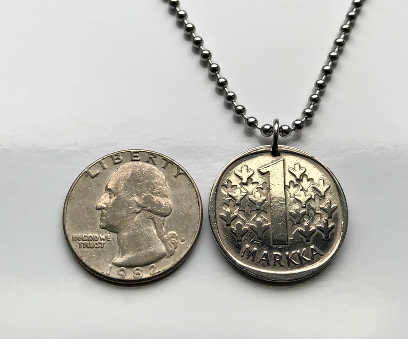 May include: A silver necklace with a silver coin pendant. The coin has the number "1" and the word "Markka" on it. The coin is from Finland.