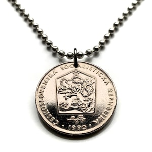 Puede incluir: Un collar de cadena de plata con un colgante de moneda de plata que presenta el escudo de armas de la República Socialista Checoslovaca con un león y el año 1990.