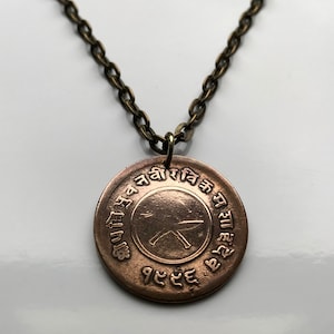 May include: A bronze necklace with a round pendant featuring a symbol and text in an unknown language. The pendant is attached to a bronze chain.