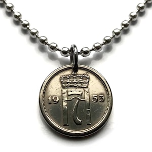 Puede incluir: Un collar plateado con un colgante de moneda. La moneda muestra una corona sobre el número "17" y el año "1953". La cadena está hecha de pequeñas cuentas redondas plateadas.