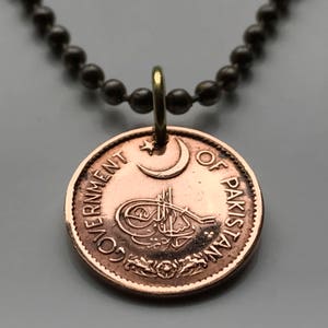 May include: A copper coin pendant necklace with a black chain. The coin features the text "Government of Pakistan" and a crescent moon and star.