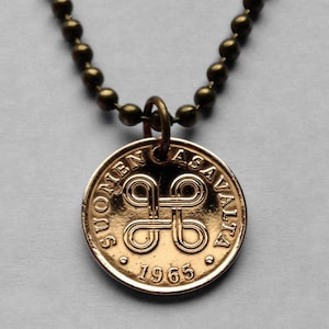 May include: A gold-coloured necklace with a pendant featuring the Finnish coat of arms and the text "SUOMEN ASAVALTA 1965".