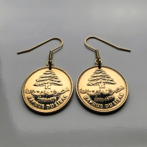 May include: Gold earrings featuring a Lebanese coin with a cedar tree and the text "Banque Du Liban" and the years "1969-1979" and "1970-1974".