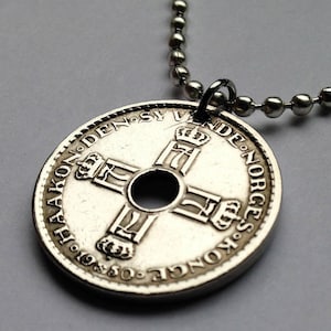 以下が含まれることがあります： ボールチェーンネックレスが付いたシルバーコインペンダント。コインには十字のデザインと、1950年を含む縁に沿ったテキストがあります。ペンダントは円形で、中央に穴があります。
