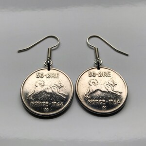 Puede incluir: Un par de pendientes plateados hechos con monedas noruegas de 50-øre. Cada moneda presenta un diseño de perro y el texto "50 ØRE" y "NORGE 1964". Los pendientes tienen ganchos para las orejas plateados.