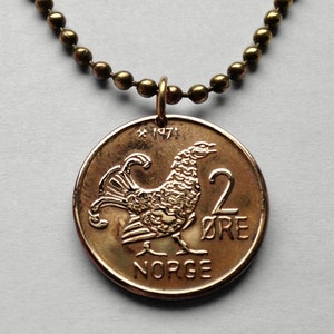 Puede incluir: Un collar de color dorado con un colgante de moneda de 2 øre de Noruega, que presenta un urogallo y el año 1971.