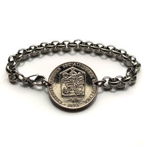 Puede incluir: Una pulsera de plata con un dije de moneda checoslovaca que presenta el escudo de armas de Checoslovaquia y el texto "Ceskoslovenska Socialisticka Republika 1973".