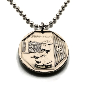 Puede incluir: Un collar de cadena de plata con un colgante de color dorado que presenta una moneda de 1 Nuevo Sol de Perú. La moneda representa una figura de cerámica de un pájaro y una llama.
