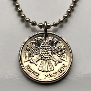May include: Silver coin pendant on a ball chain necklace. The coin features a detailed double-headed eagle design and Cyrillic text. The pendant is suspended from a silver-colored ball chain.