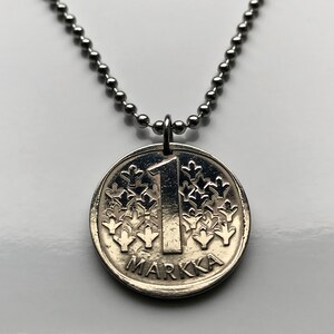 May include: A silver necklace with a silver coin pendant featuring the number "1" and the word "MARKKA".
