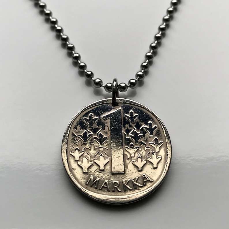 May include: A silver necklace with a silver coin pendant featuring the number "1" and the word "MARKKA".