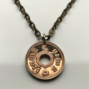 May include: A gold-toned necklace with a coin pendant featuring a snake design and Thai script. The coin has a hole in the center and is attached to a bronze chain.