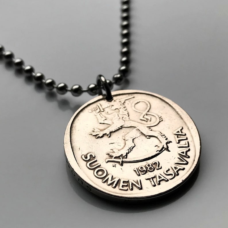 May include: A silver necklace with a silver coin pendant featuring a lion and the text "SUOMEN TASAVALTA 1982".