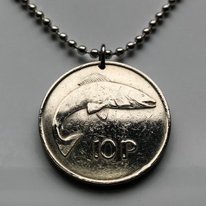 May include: A silver-colored pendant necklace featuring a coin with a fish design. The coin has the text "10P" on it. The necklace chain is made of small, round, silver-colored beads.