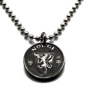 Puede incluir: Un collar de cadena de plata con un colgante de moneda de plata que presenta el escudo de armas noruego y la palabra "NORGE" inscrita alrededor del borde.