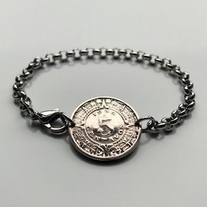 May include: A silver bracelet with a silver coin charm. The coin has the year 1936 and the number 5 on it.