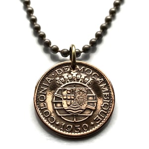 Puede incluir: Un collar con colgante de moneda de color cobre. La moneda presenta texto y un diseño de escudo. El collar tiene una cadena de bolas y un cierre color latón. La moneda está fechada en 1950.
